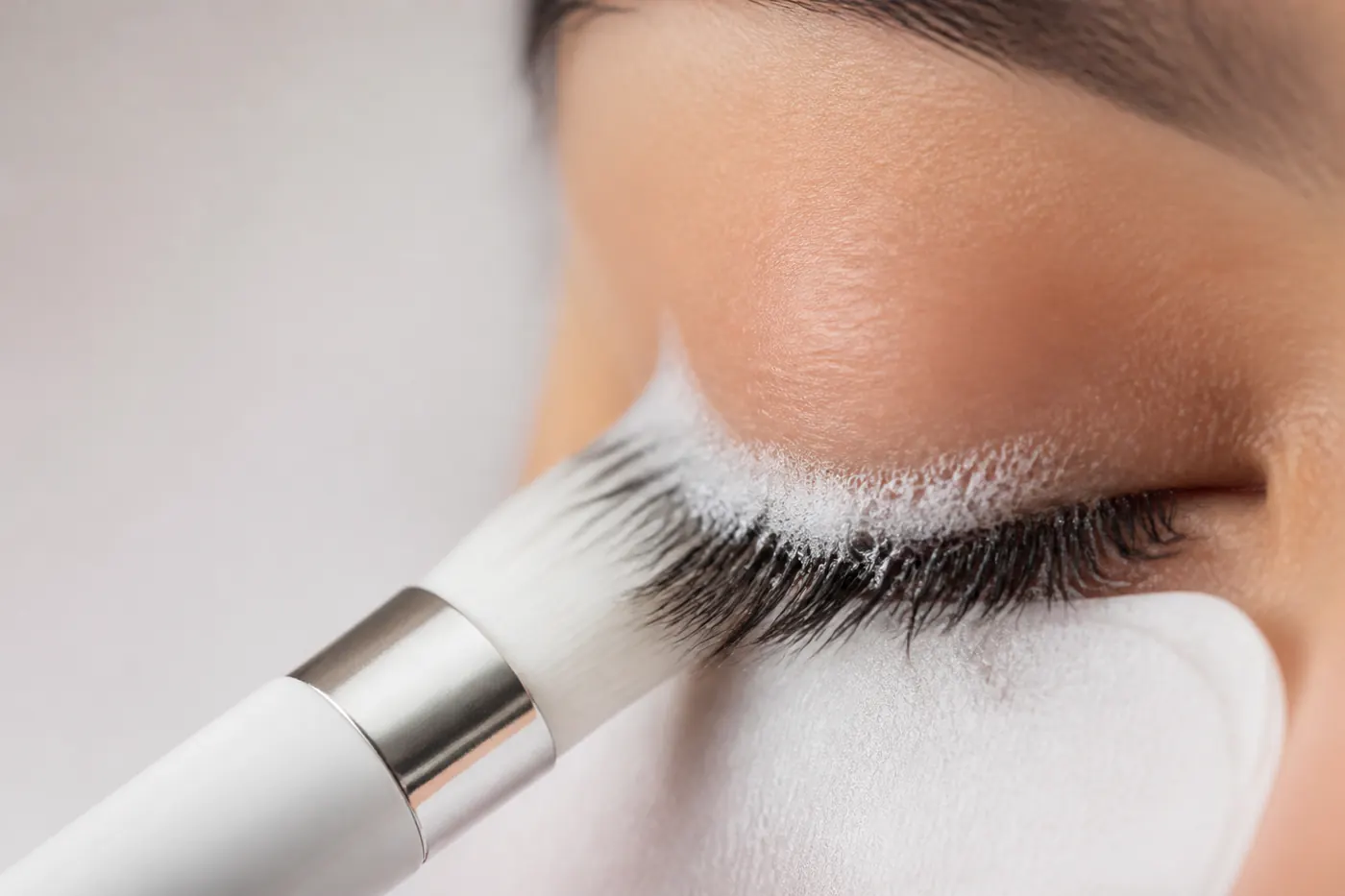 Macro photograph of a soft angled lash brush working foam along the lash line
