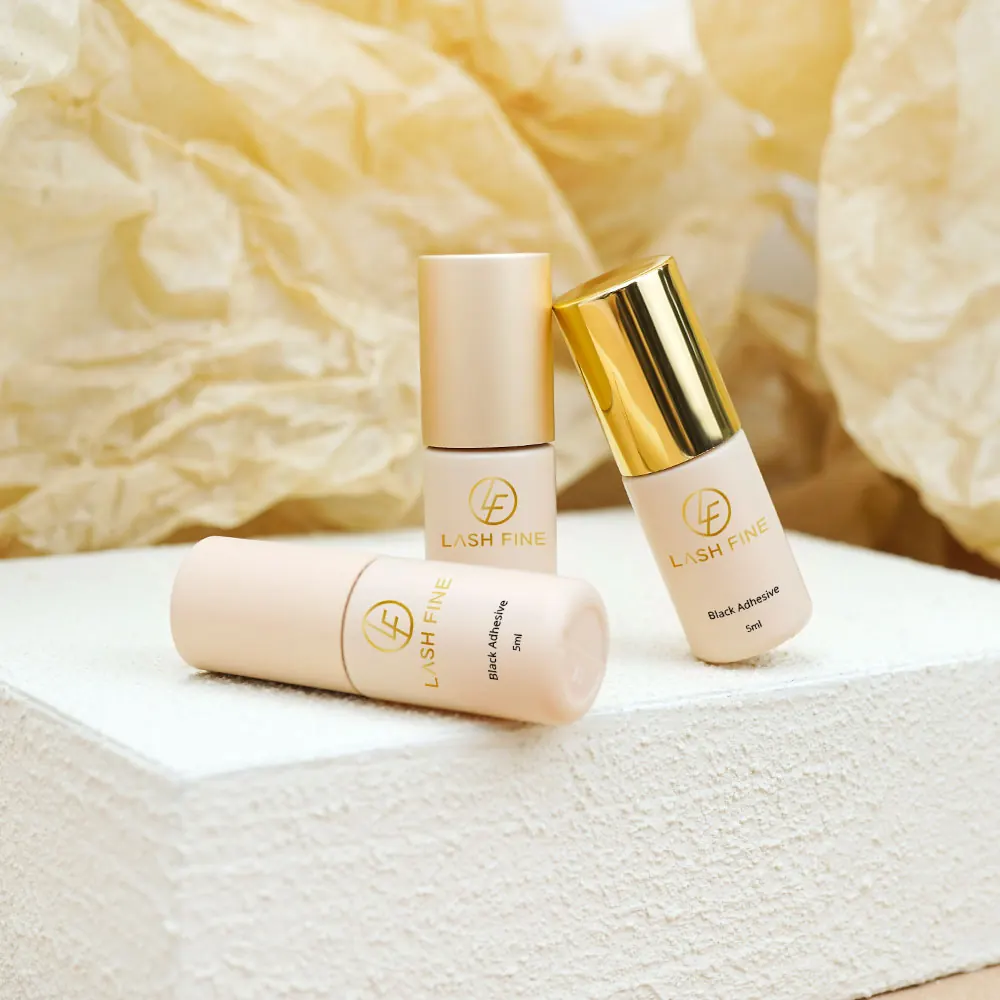 Three Lash Fine black adhesive bottles staged on a plaster block with gold paper