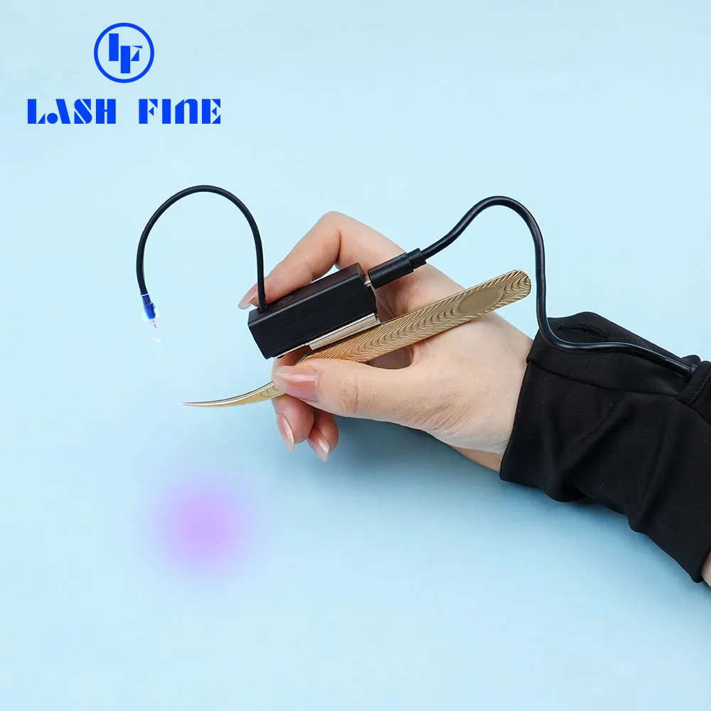 Hand holding the Lash Fine UV LED tweezer lamp switched on beside lash tweezers